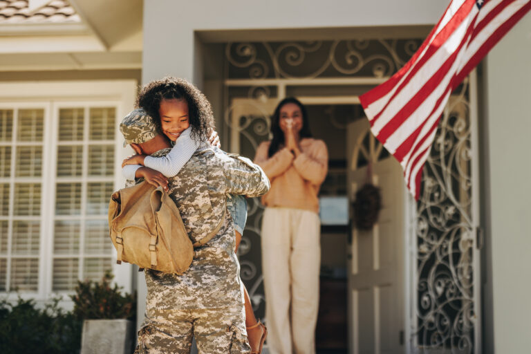 A father hugging a child after returning from a military campaign.