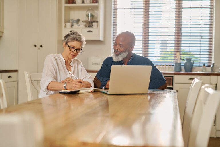 Cropped shot of a happy mature couple using a laptop while going over their bills and finances together at home